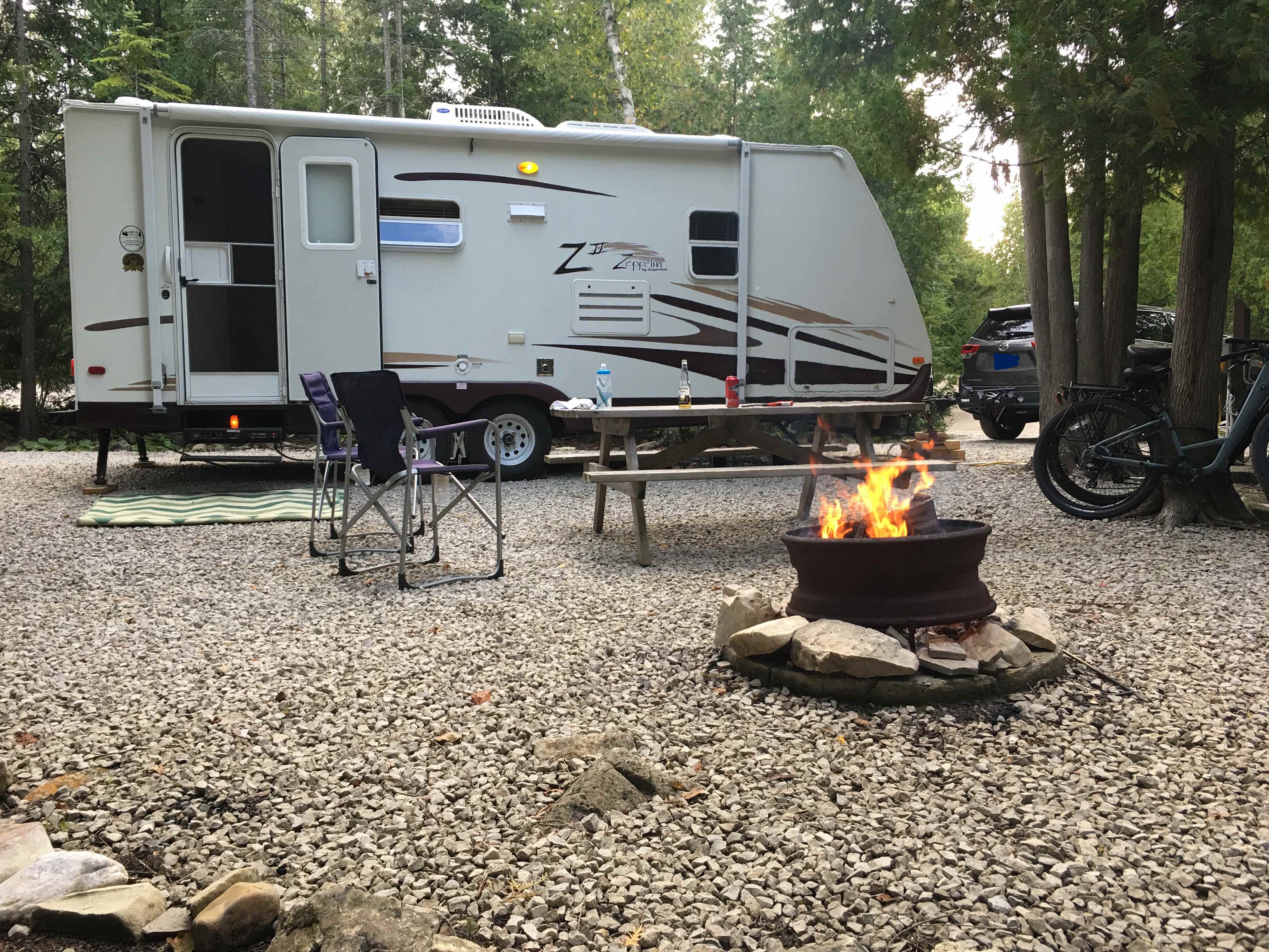 A camper with a fire pit in front of itDescription automatically generated with low confidence